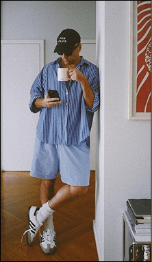 Model in a striped shirt holding a cup indoors