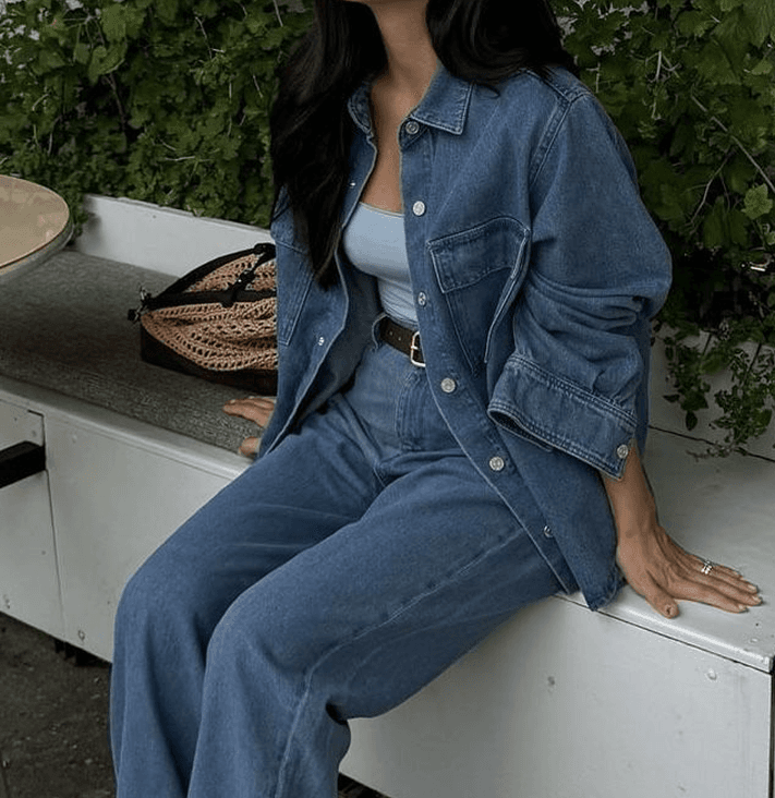 Model sitting in denim beside greenery